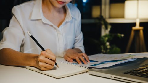 Seorang karyawan sedang menghitung upah lembur di kantor